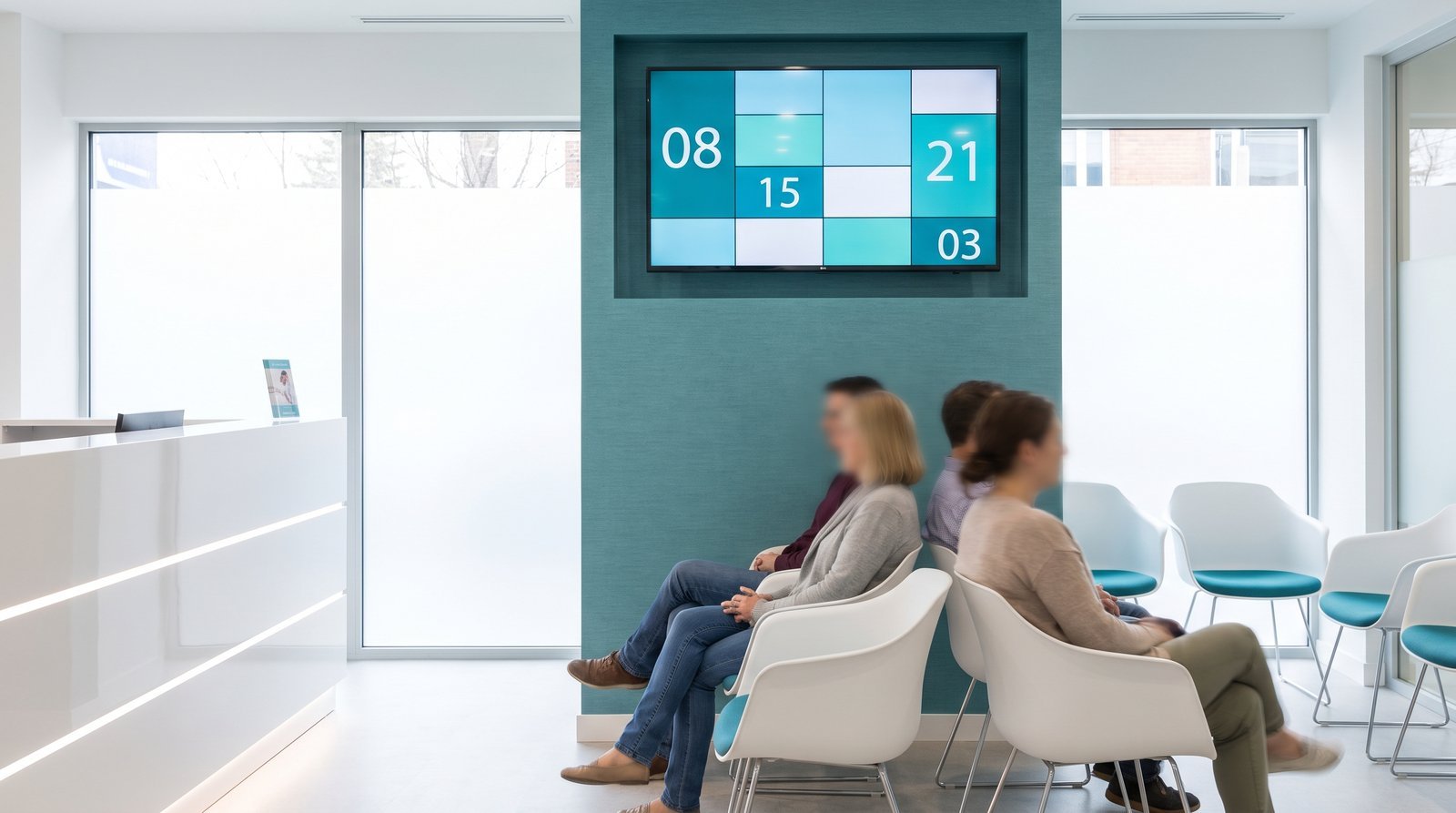 Recepção de clínica com TV exibindo painel de senhas